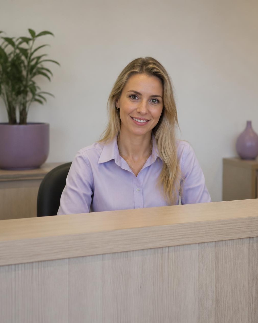 Secretária sorrindo atrás do balcão da recepção de uma escola